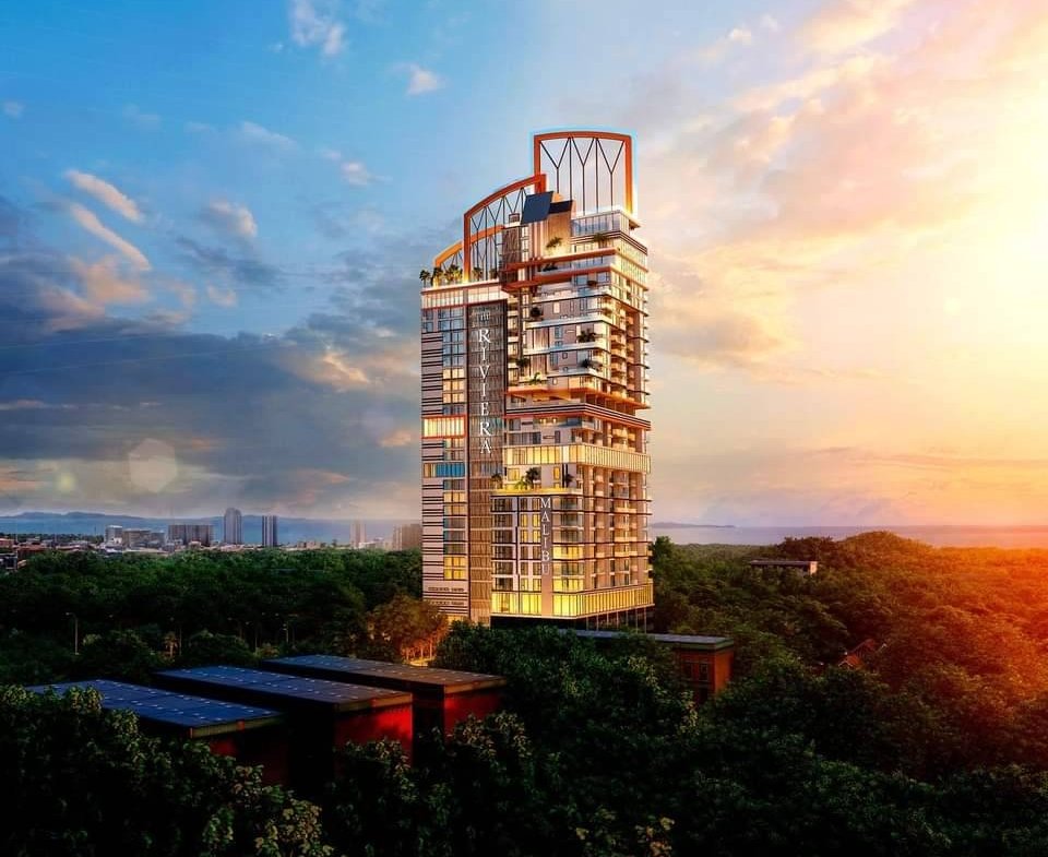 Modern high-rise residential tower rising from a green forest at sunset