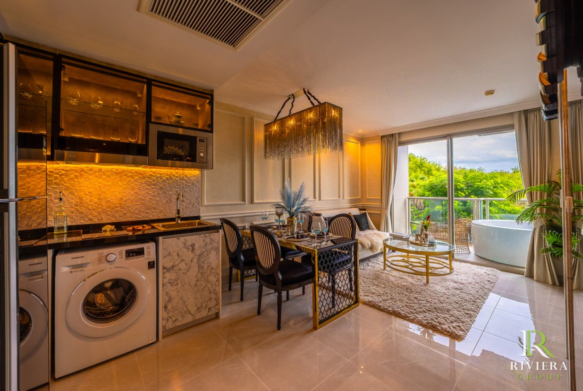 Open-plan kitchen and dining area with marble counters, glass-front cabinets, and a large hanging pendant light overlooking a living area and balcony.