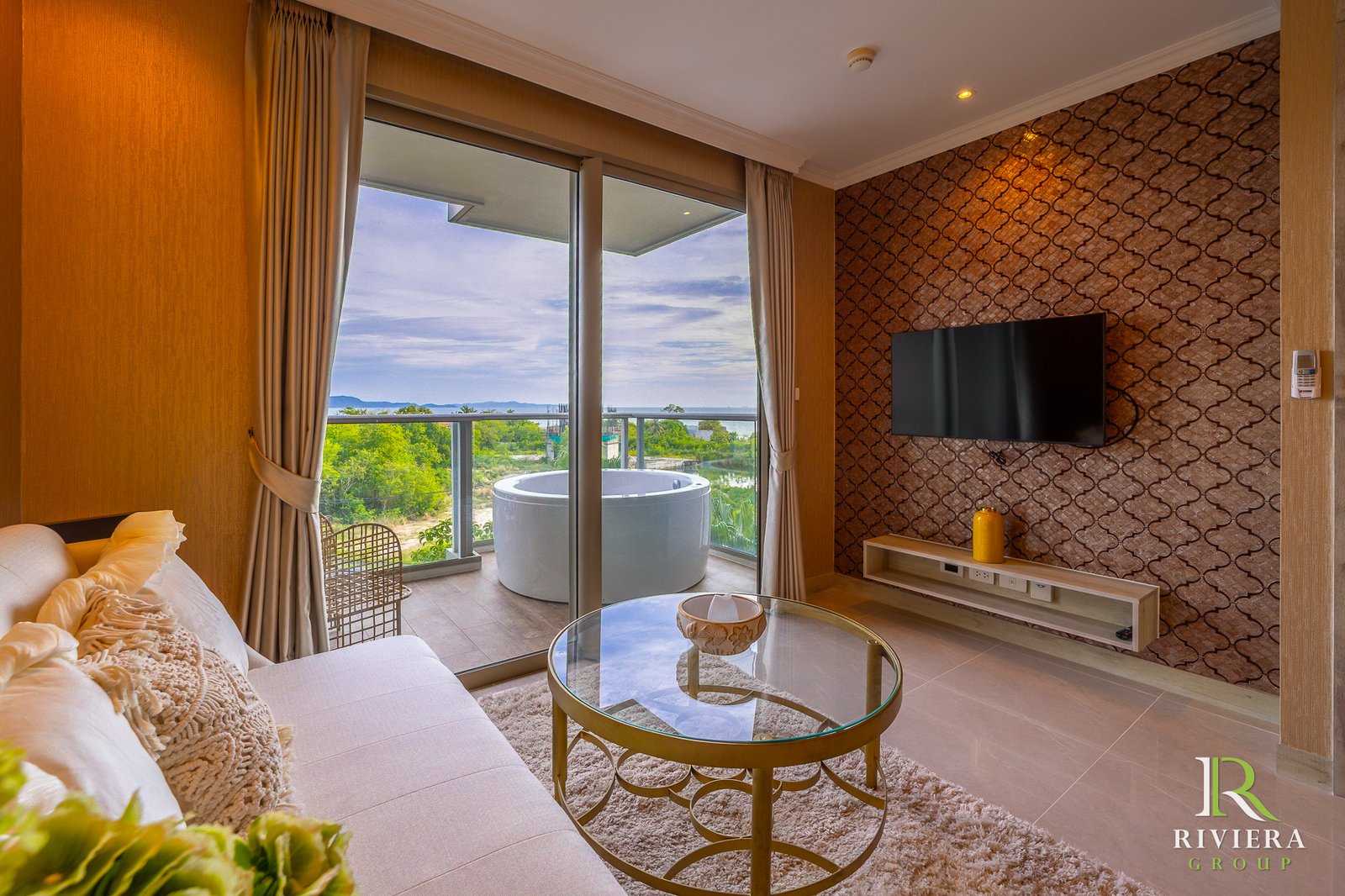 502-S06 Hotel living room with cream sofa, glass coffee table, and a balcony door that frames an ocean view.