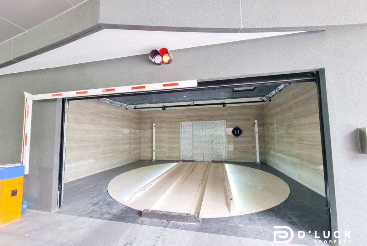 Open car lift with a circular rotating platform inside a tiled garage, walls in beige tiles, doorway visible on the back wall.