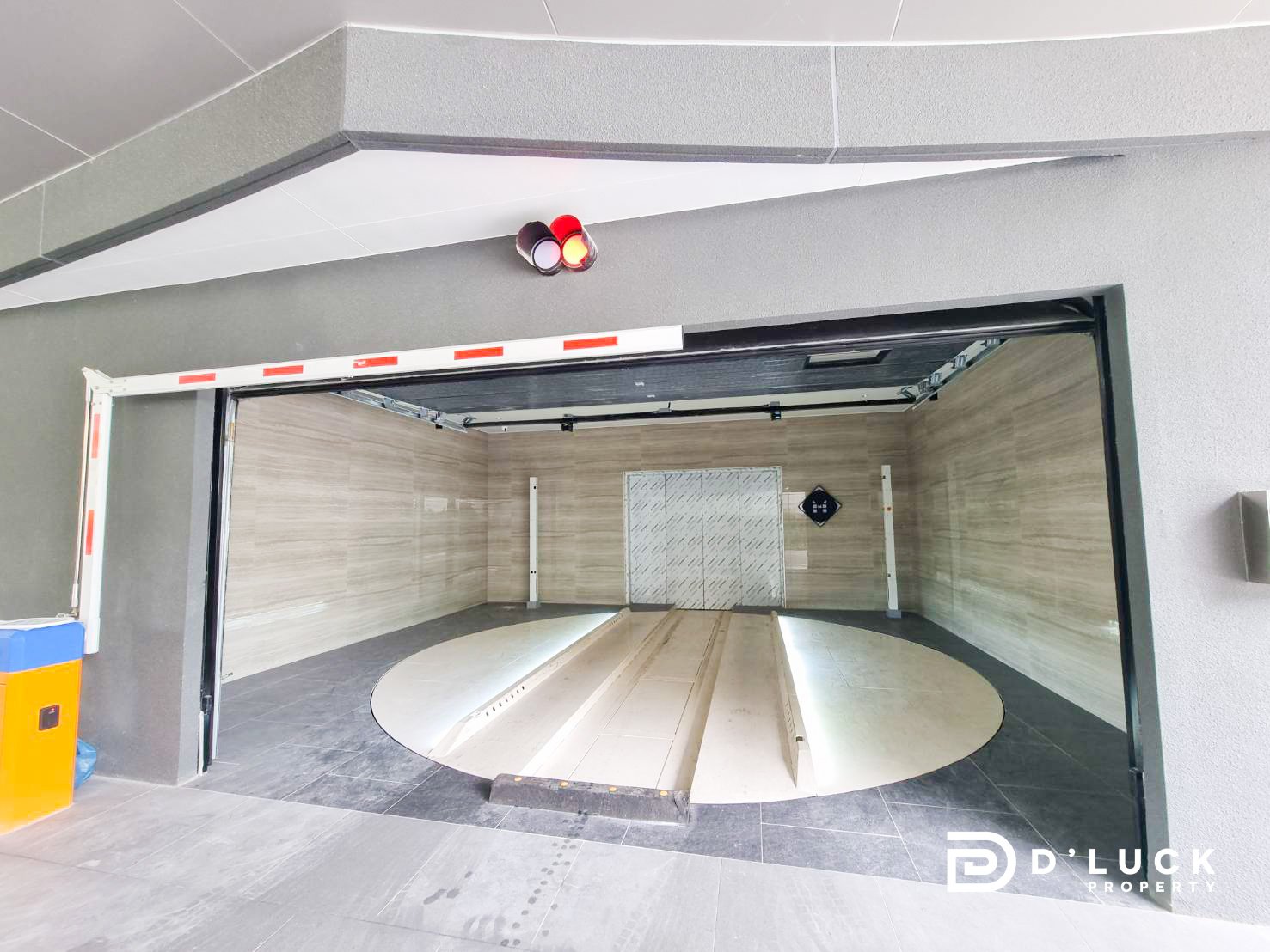 AW Common area 42 Open car lift with a circular rotating platform inside a tiled garage, walls in beige tiles, doorway visible on the back wall.