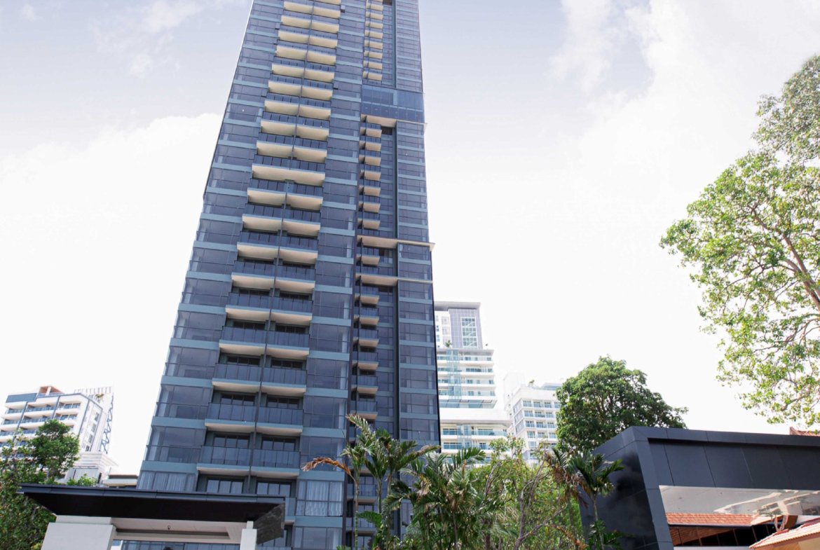 Tall blue glass high-rise with balconies under a clear sky; gold Andromeda logo appears in the top left corner.