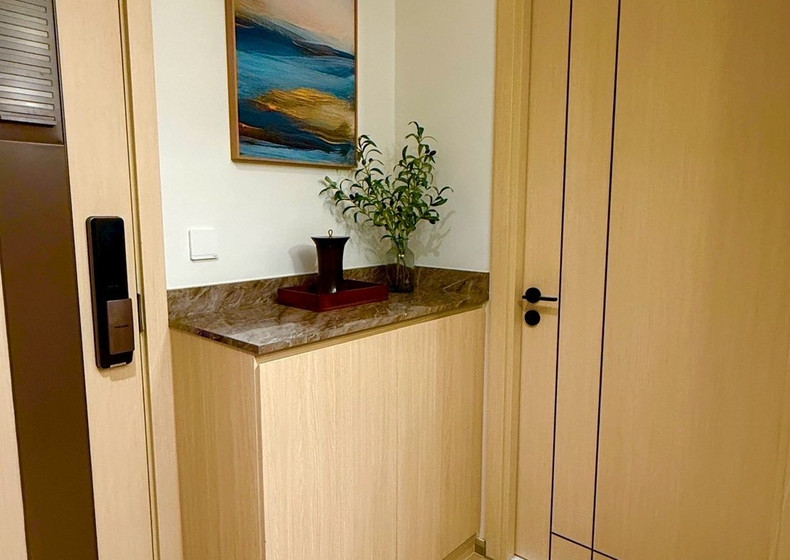 Corner hallway with a marble-topped cabinet, a small vase and green plant against a white wall with an abstract painting above it