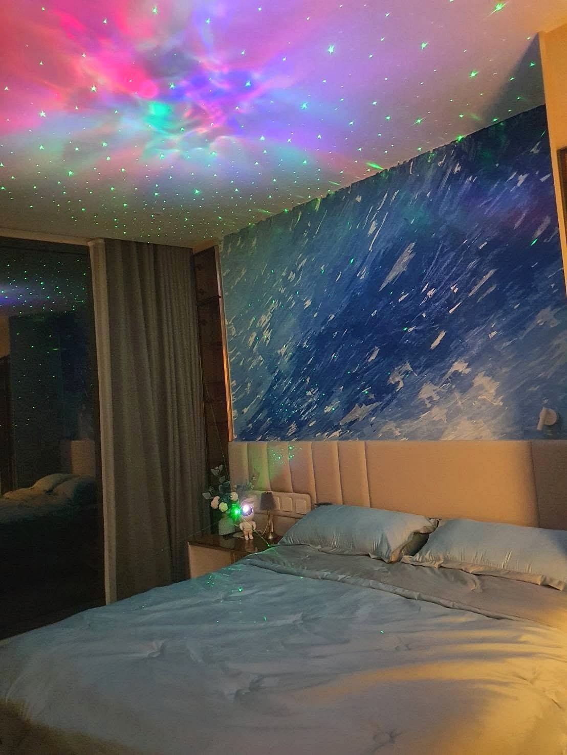 Arom_Wongamat_1bed_Rent_Rdl334_6 Bedroom with blue wave mural, starry ceiling projection, and a large bed with blue sheets; nightstand and lamp at the headboard.