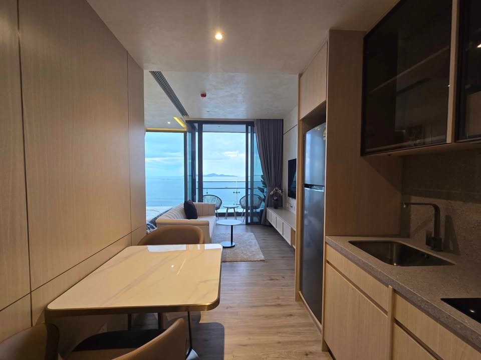 Open-plan kitchen and living area with a balcony door open to a sea view.