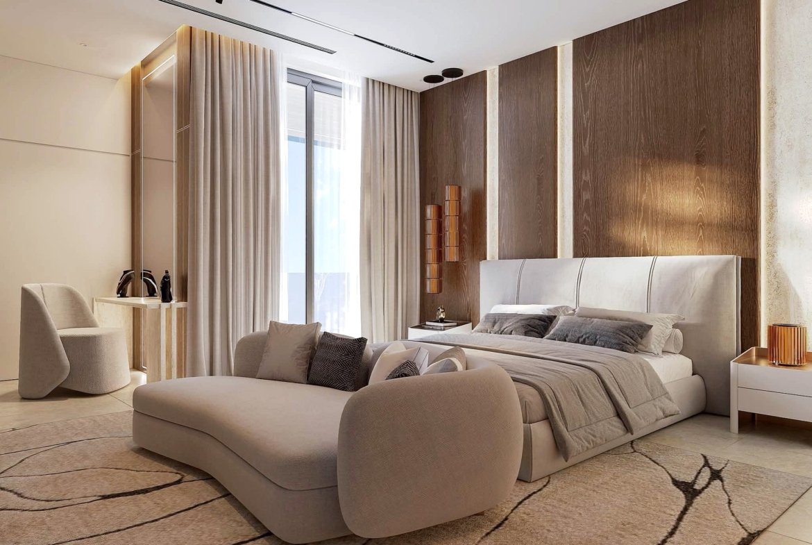 Luxurious hotel bedroom with beige upholstered seating, a large patterned rug, and wooden paneled walls behind a plush bed.