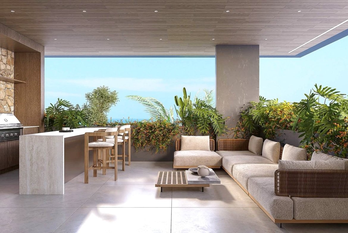 Outdoor living area with a built-in grill, bar counter, and beige sectional seating amid lush tropical plants and a wood-paneled ceiling.