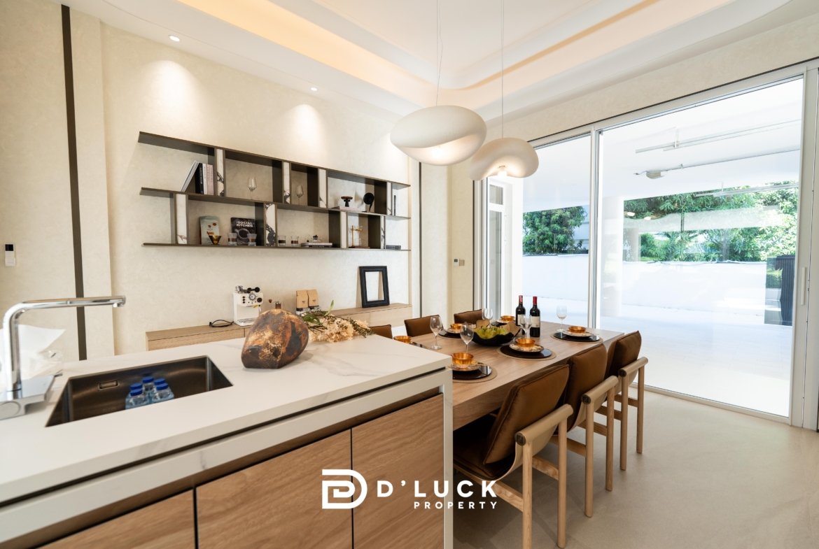 Bright, modern kitchen and dining area with a wood-and-marble island, wall shelves, and a large glass sliding door opening to a garden outdoor space.