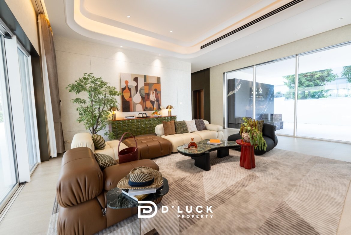 Contemporary living room with a cream leather sectional, abstract art on the wall, a tall green plant, and floor-to-ceiling windows letting in light.