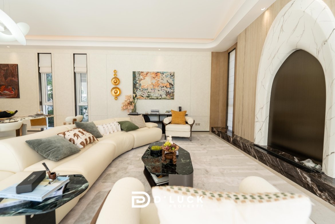 Bright modern living room with a curved white sectional sofa, marble coffee tables, and abstract wall art under soft natural light.