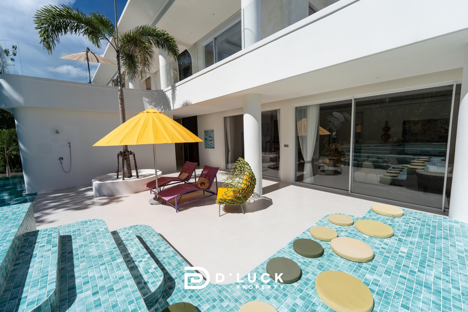 Big_V_Pattaya_Type_A_55 Modern luxury villa pool area with turquoise tiled steps, a bright yellow umbrella, and purple lounge chairs under a blue sky.