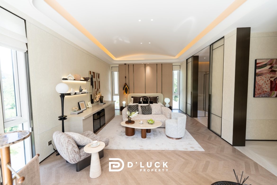 Bright modern living room with beige walls, cream furniture, and round marble coffee table; D’Luck Property logo visible at bottom.