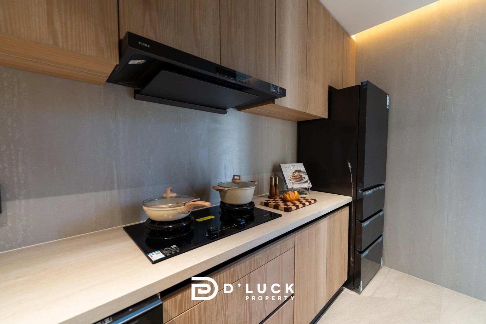 Big_V_Pattaya_Type_A_74 Modern kitchen with a black induction cooktop, two pots, and wooden cabinets above and below the counter.