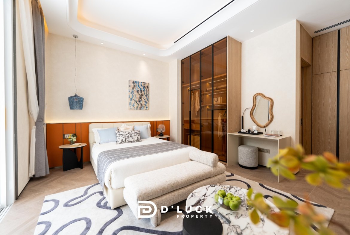 Luxurious bedroom with a white bed, orange headboard, and blue-gray pillows in a bright modern suite.