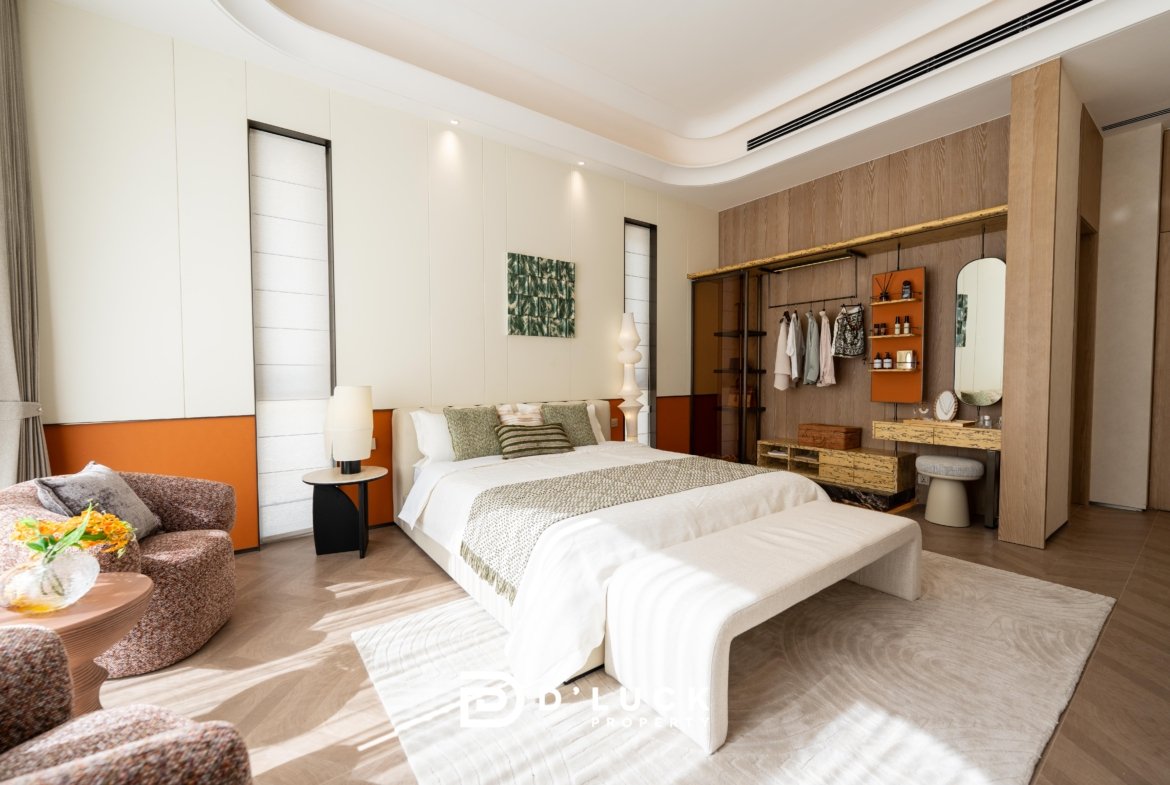 Hotel bedroom with two neatly made beds, warm neutral tones, and a sitting area with patterned chairs.