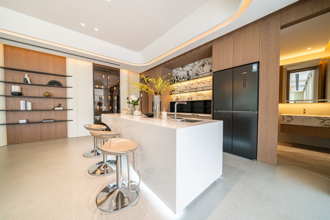 Modern open-concept kitchen with a white island, beige bar stools, and marble backsplash