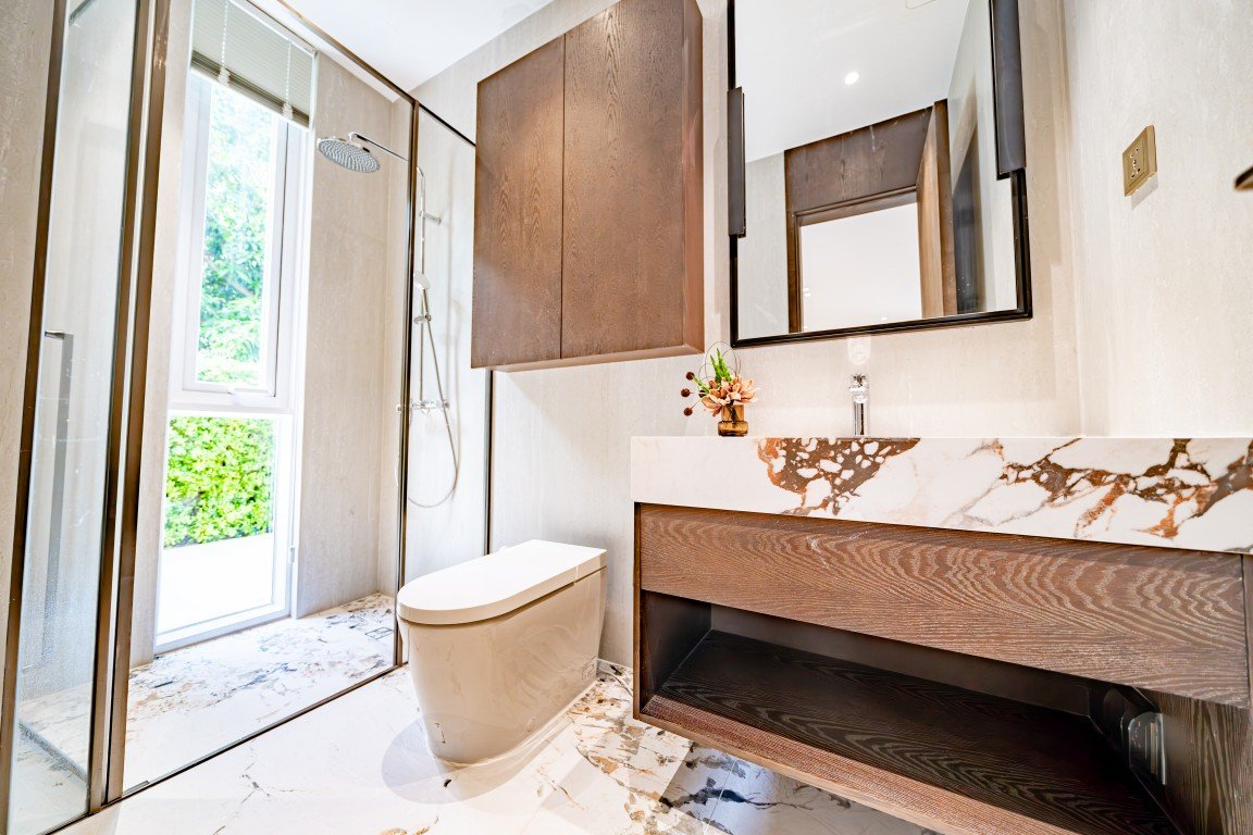 Contemporary bathroom with glass-enclosed shower, wall-mounted vanity with marble countertop, and a through-window letting in natural light.
