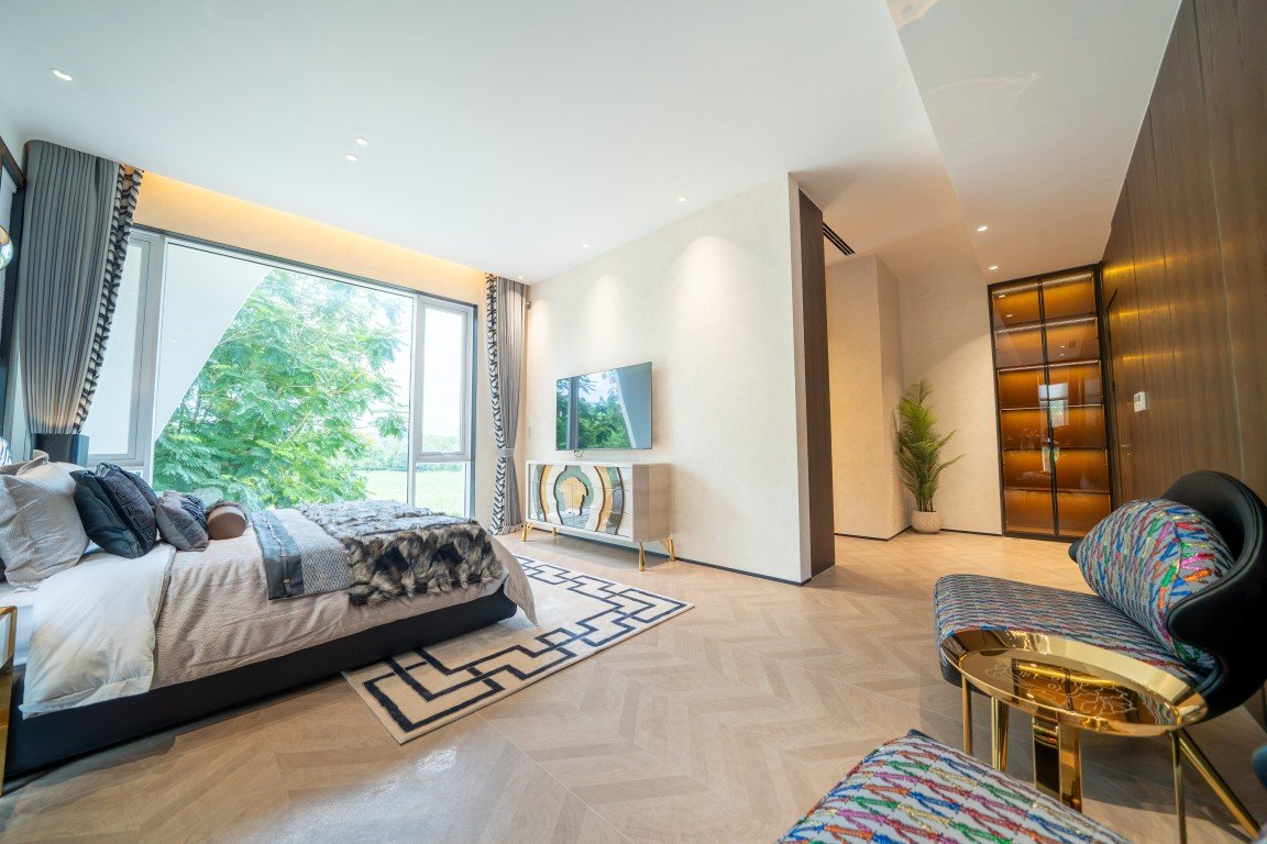 Bright hotel-style bedroom with a large window, plush bed, and a seating area bathed in natural light.
