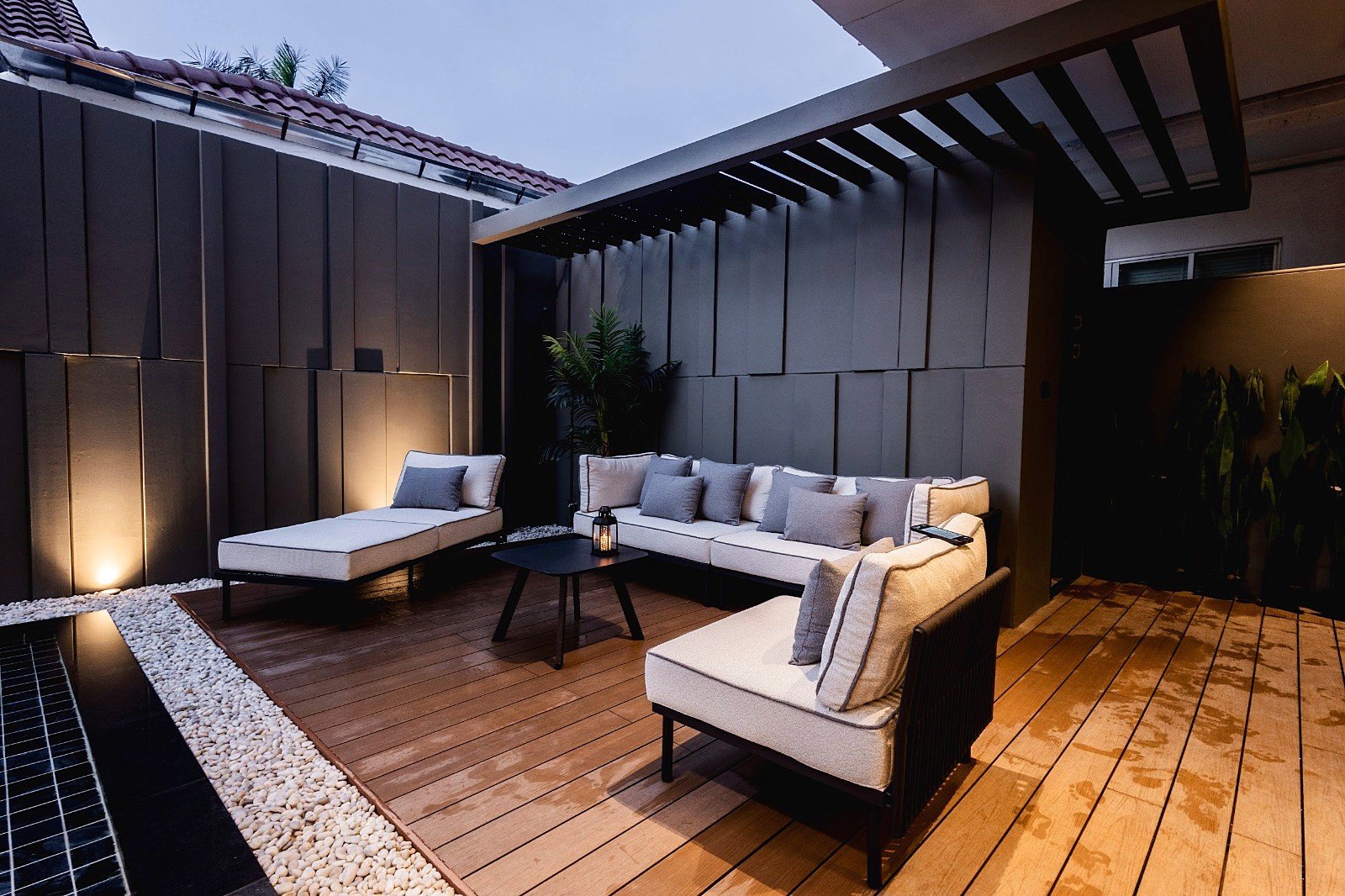 Casa_Jomtien_Village_Rent_Rdl352_42 Modern outdoor seating area on a wooden deck with gray sectional sofa and neutral cushions.