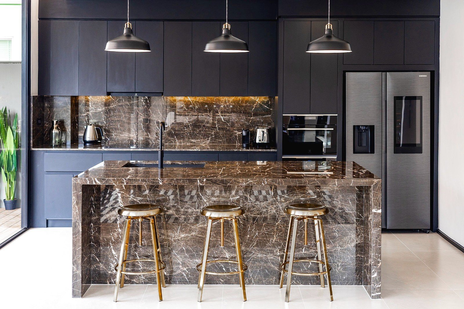 Casa_Jomtien_Village_Rent_Rdl352_7 Modern black kitchen with a marble island and matching backsplash, three gold bar stools, and stainless appliances.
