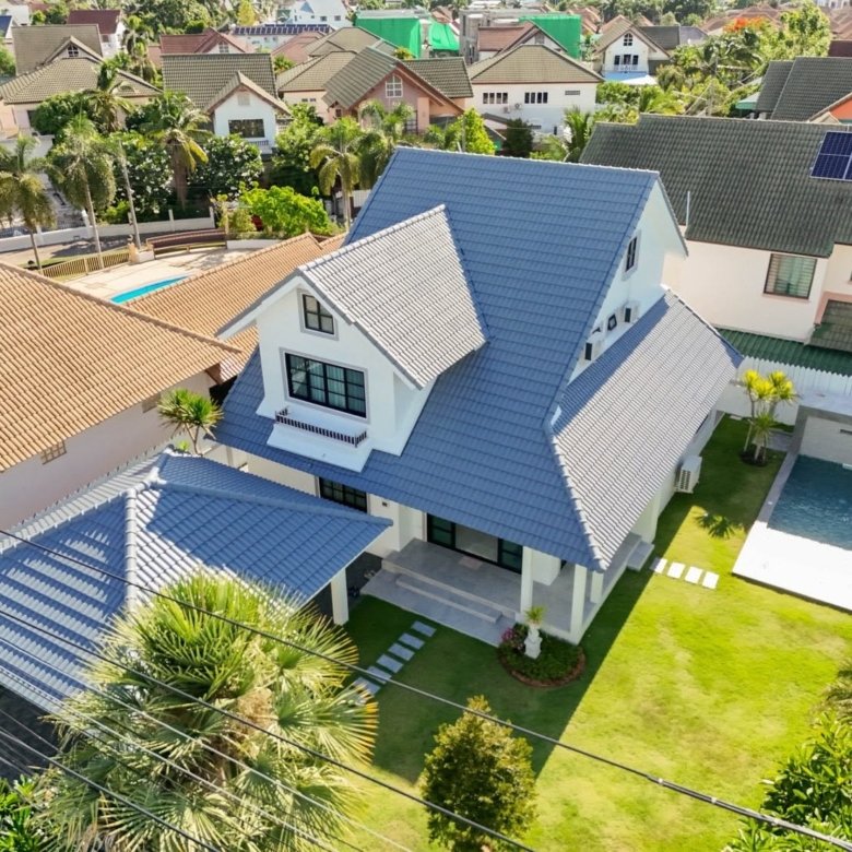 Aerial view of a white two story house with a blue tile roof and manicured front yard