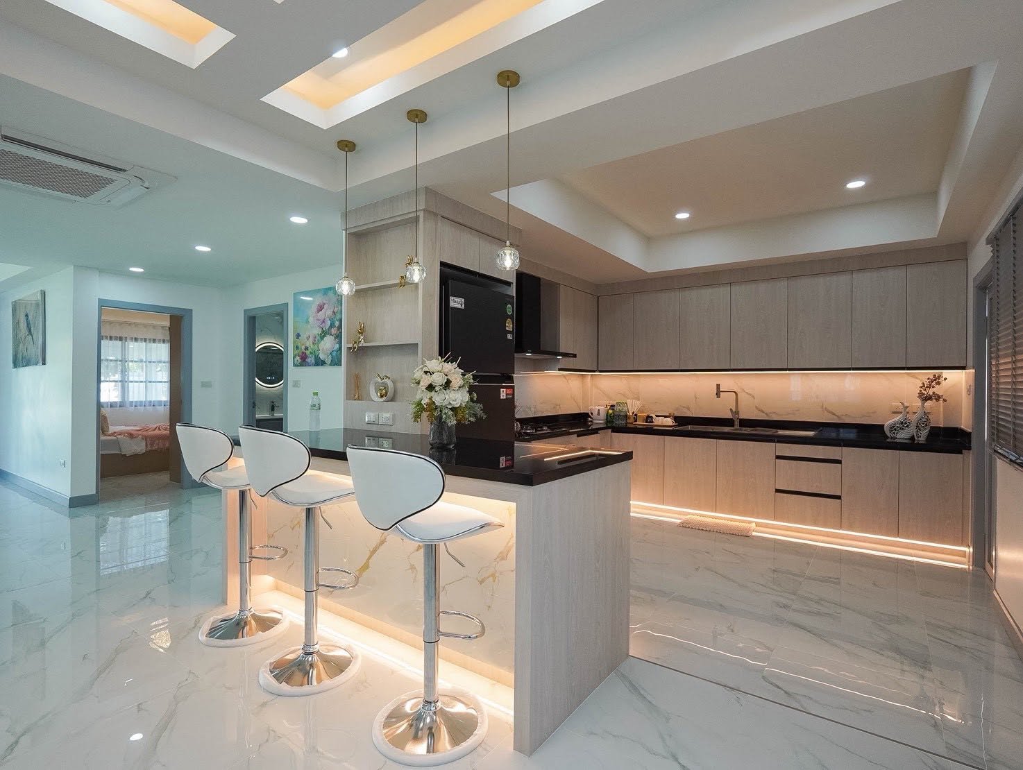 Central_Park_5_Pattaya_Sale_Dlh506_13 Open-plan modern kitchen with a light wood island, three white bar stools, marble floor, and under-cabinet lighting.