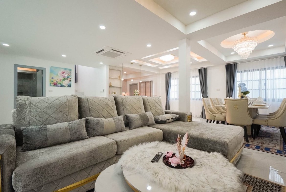 Open-concept living and dining area with a plush gray sectional, white marble coffee table, and a fur centerpiece in a bright, modern home.