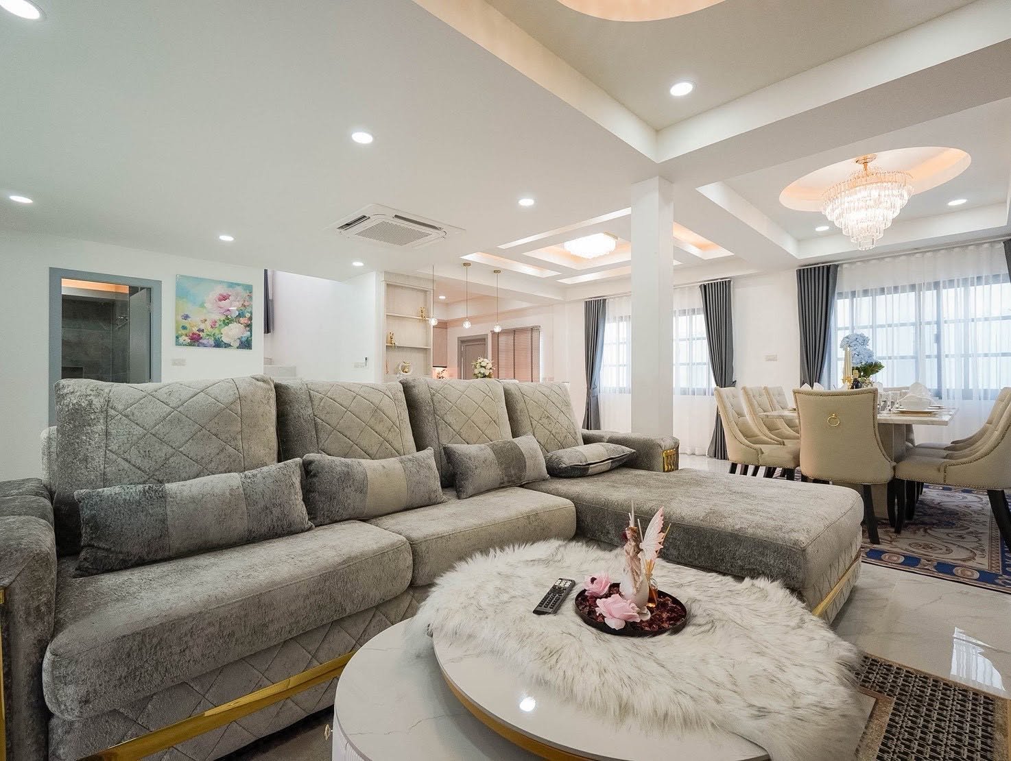 Central_Park_5_Pattaya_Sale_Dlh506_20 Open-concept living and dining area with a plush gray sectional, white marble coffee table, and a fur centerpiece in a bright, modern home.
