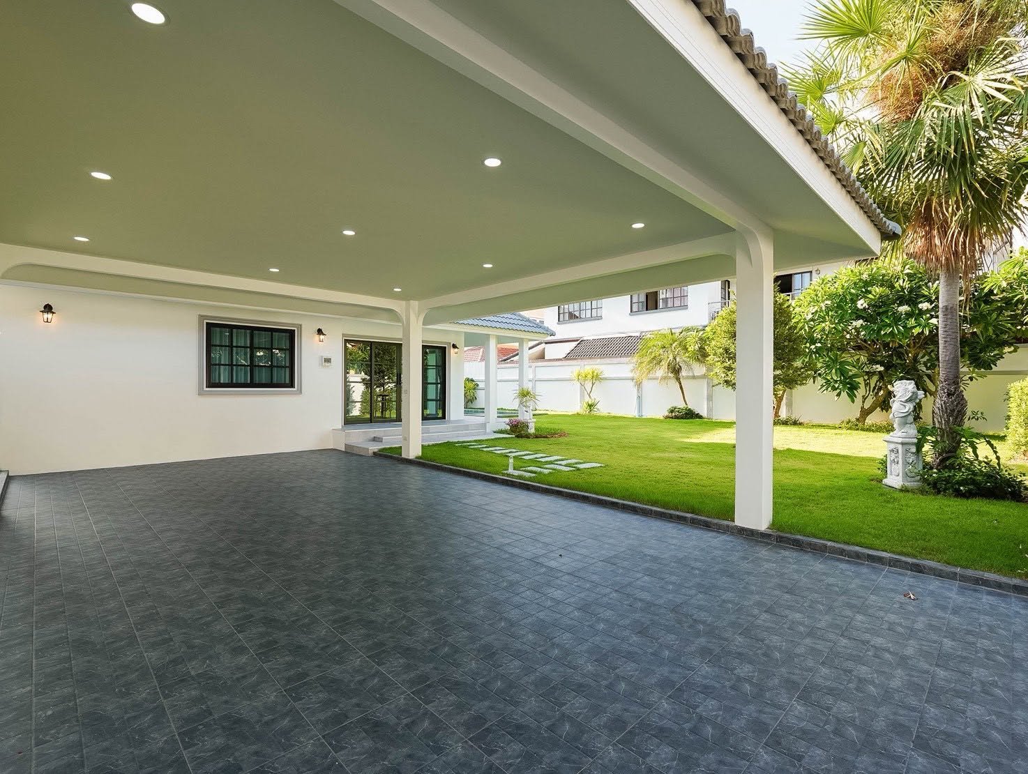 Central_Park_5_Pattaya_Sale_Dlh506_22 Covered patio with white columns and recessed lights, opening to a green lawn and palm trees.