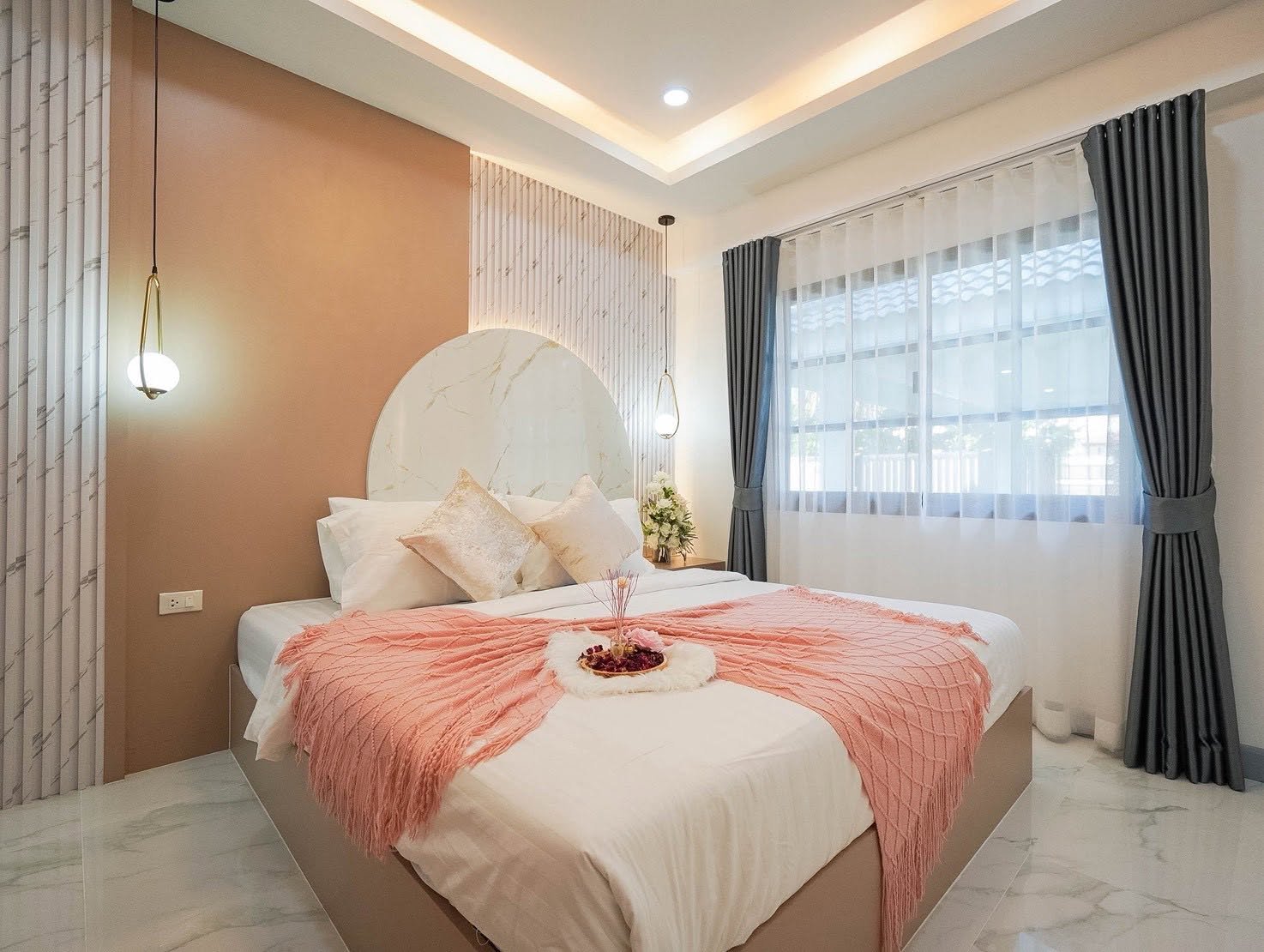 Central_Park_5_Pattaya_Sale_Dlh506_5 Bedroom with a round marble headboard, pink accent wall, white bedding, and a pink throw blanket.