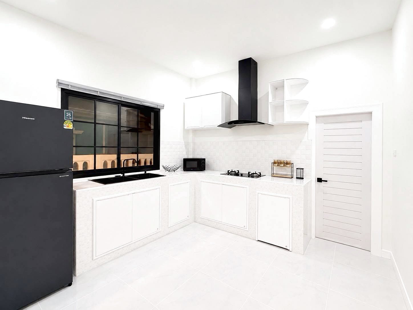 Bright, modern white kitchen with a black side-by-side fridge, gas stove, range hood, and white cabinets along two walls