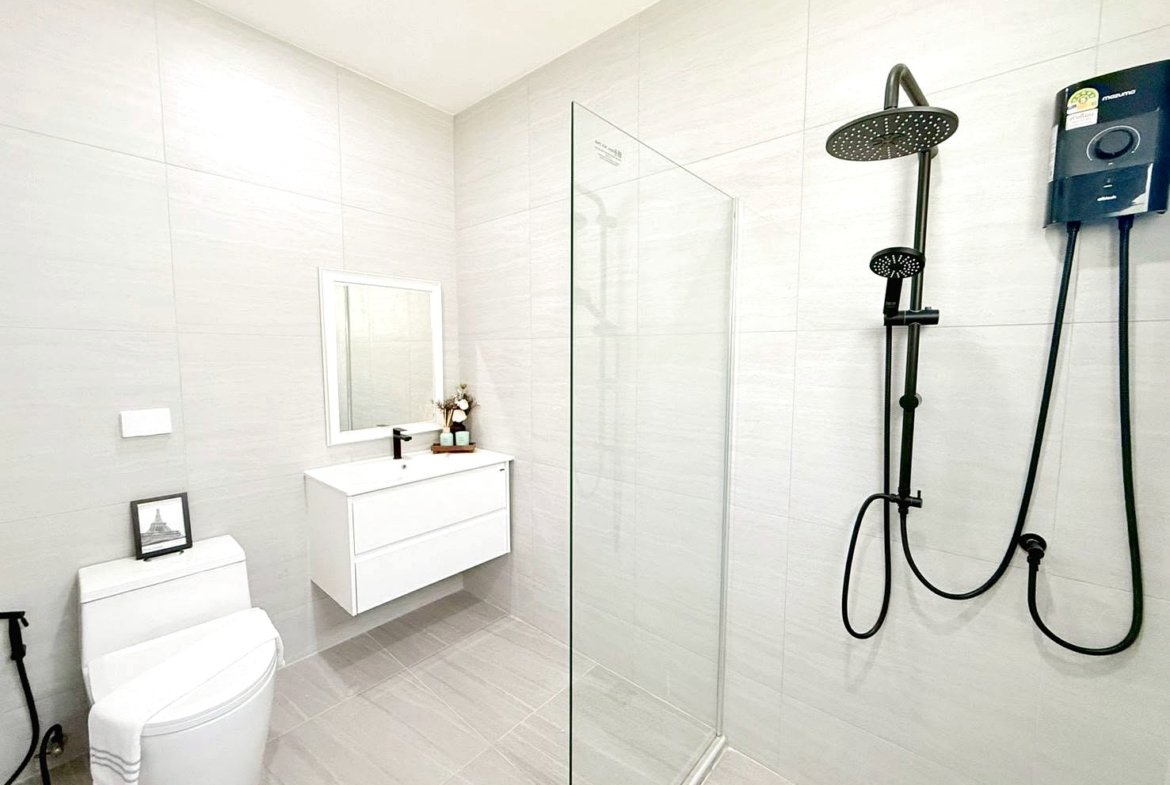 Modern white bathroom with a glass shower enclosure, wall-hung vanity, mirror, and a black rainfall shower system.
