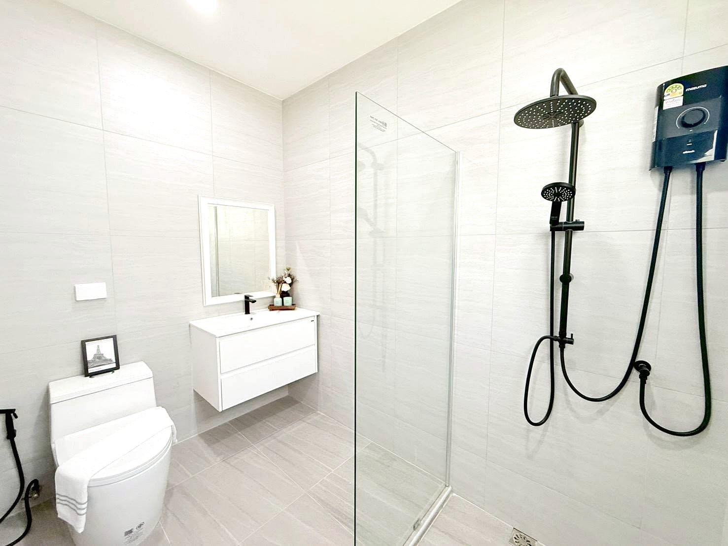 Modern white bathroom with a glass shower enclosure, wall-hung vanity, mirror, and a black rainfall shower system.