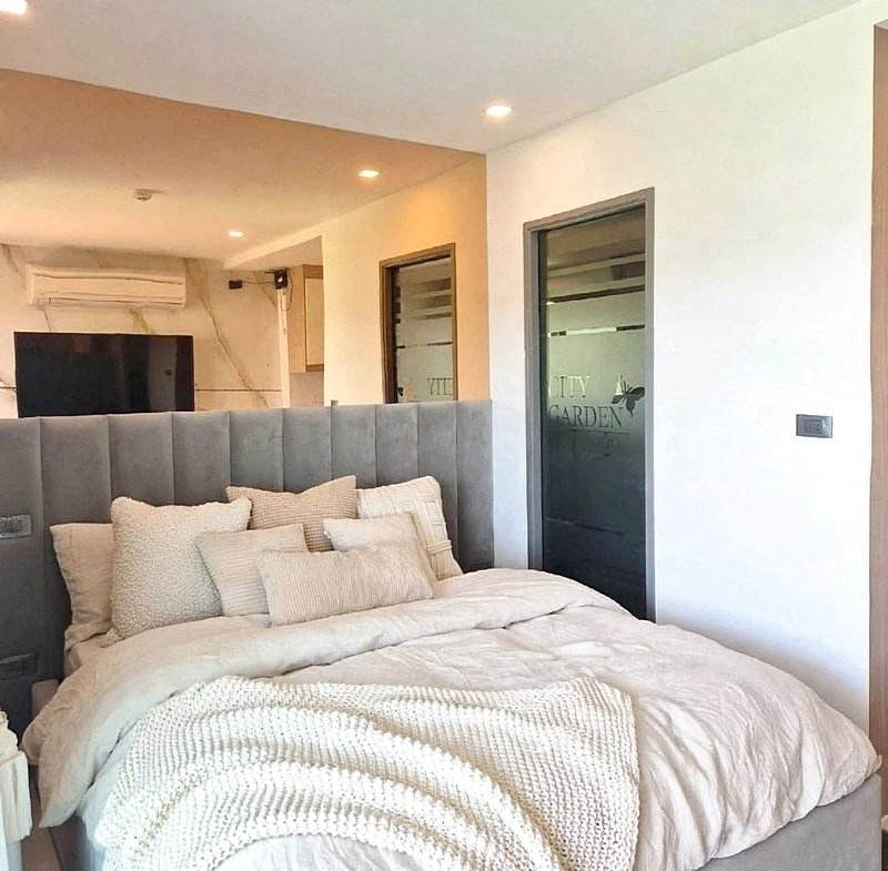 Cozy modern bedroom with a tall gray upholstered bed, white bedding, and multiple cream pillows.