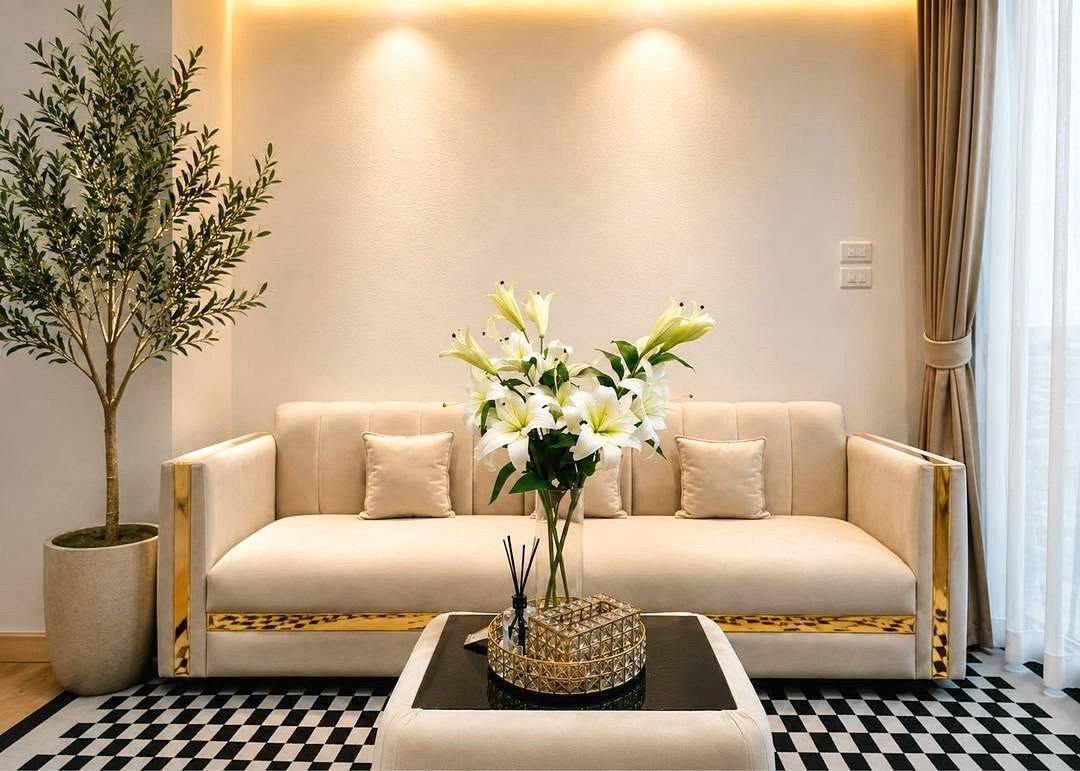 Beige living room with a cream sofa, white lily bouquet on a glass coffee table, and a black-and-white checkered rug.