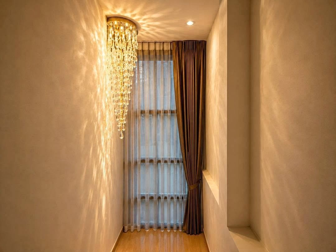 Deperfect_Village_a1_Rdl365_9 Narrow hallway with a crystal chandelier casting light on pale walls, sheer white curtains and brown drapes over a tall window.