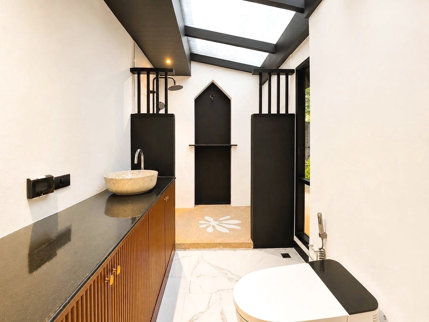 Dharawadi_Poolvilla_Rent_Rdl353_41 Modern bathroom with a circular stone sink on a dark countertop, wooden cabinet, and a skylight overhead.