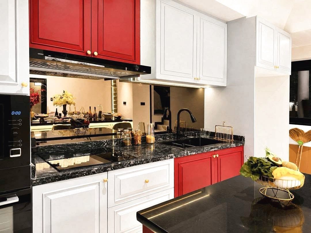 Dharawadi_Poolvilla_Rent_Rdl353_5 Modern kitchen with white lower cabinets, red upper cabinets, and black marble countertops surrounding a black sink and faucet on the right.