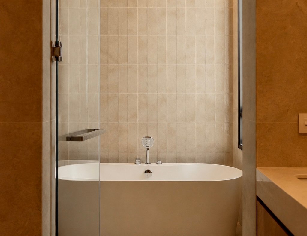 Modern bathroom featuring a freestanding oval tub beneath tiled walls, with a glass shower enclosure and a ceiling-mounted rainfall showerhead.