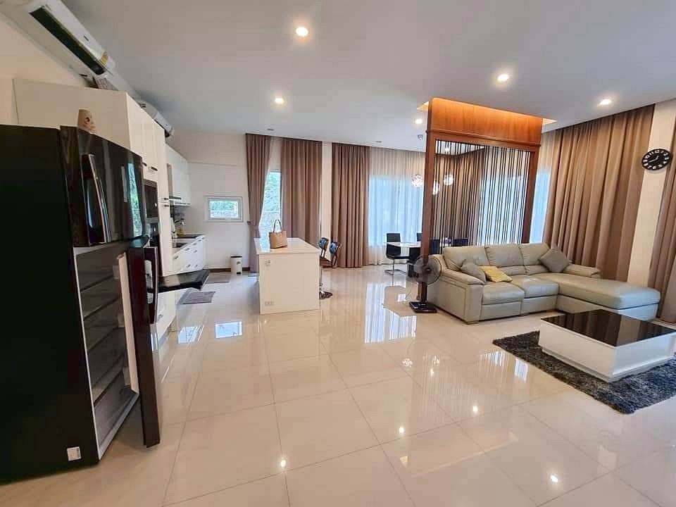 Open-concept living area with white glossy tile floors, a gray sectional sofa, and a white coffee table near a dark rug.