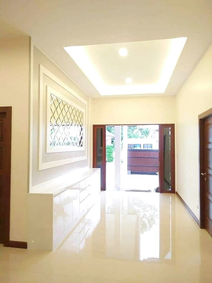 Garden_Ville_1_Pattaya_Rent_Rdl368_13 Bright, modern hallway with a glossy white floor, built-in white cabinet, decorative lattice window, and open French doors to outdoors.