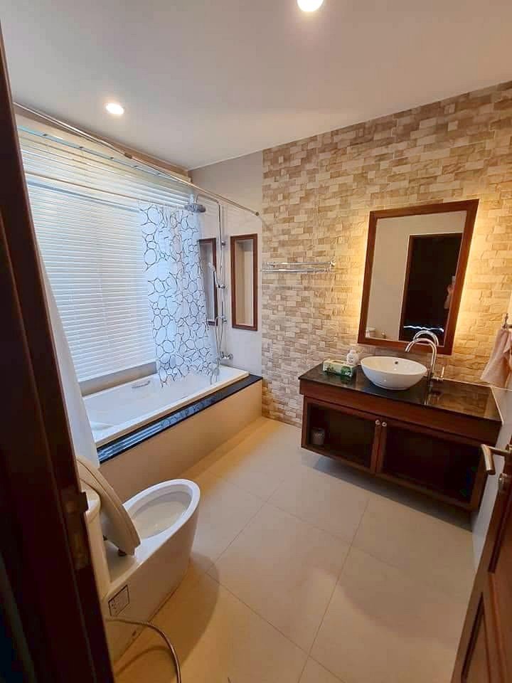 Garden_Ville_1_Pattaya_Rent_Rdl368_7 A modern bathroom with a bathtub along a window and a frosted glass shower curtain, plus a toilet in the foreground.