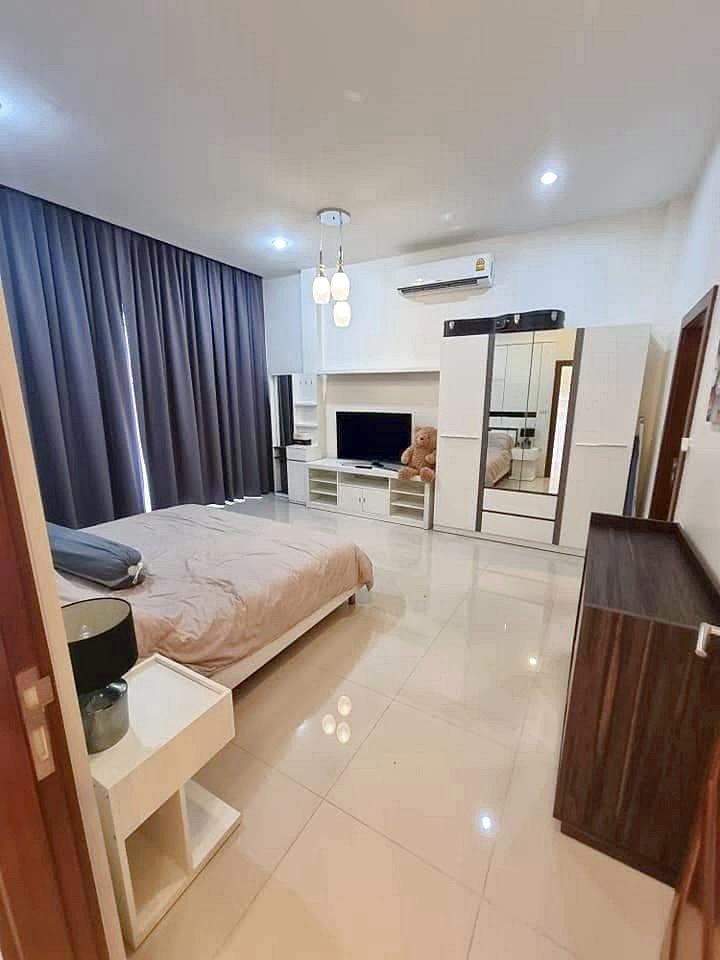 Garden_Ville_1_Pattaya_Rent_Rdl368_8 Modern bedroom with a low bed, beige bedding, dark floor-to-ceiling curtains, and glossy white tiled floor.