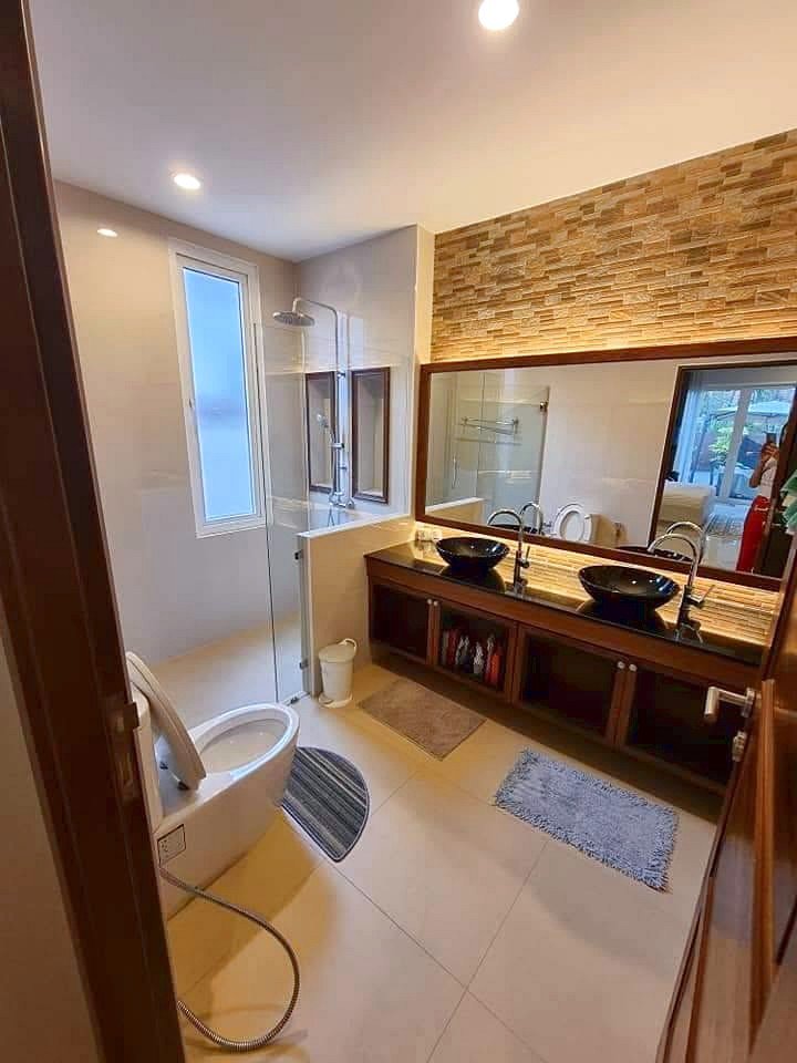 Garden_Ville_1_Pattaya_Rent_Rdl368_9 Modern bathroom with double sinks, large mirror, and glass shower; stone accent wall above the vanity.