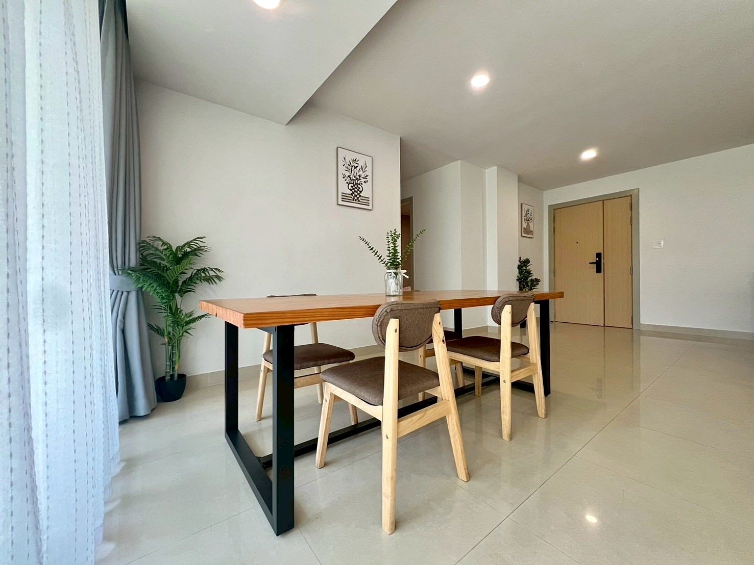 Gardenia_Pattaya_4Bed_Dlc492_26 Minimalist dining area: long wooden table with black legs, three wooden chairs, and a potted plant in the corner.