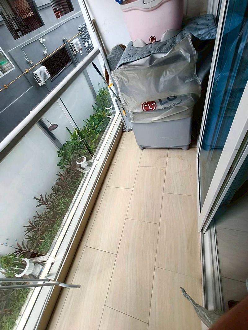 Grand_Avenue_Pattaya_Sale_Dlc641_11 Narrow balcony storage area with a gray LG bag on a cabinet, a pink tub on top, and potted plants along a glass railing.