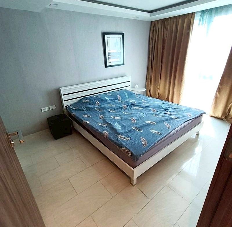 Modern bedroom with a white platform bed, blue feather-pattern sheets, a framed wall art, and a white nightstand beside it.