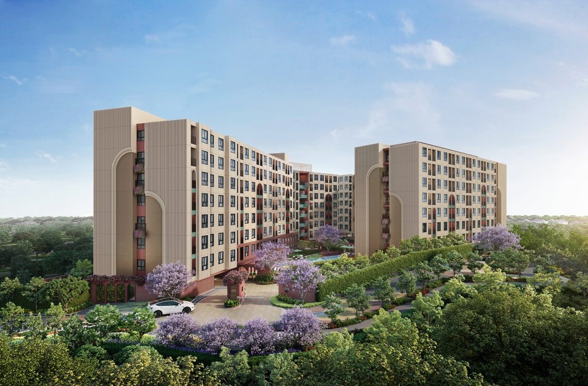 Modern beige apartment complex with curved towers, surrounded by lush landscaping and flowering trees; a driveway and car at the entrance.