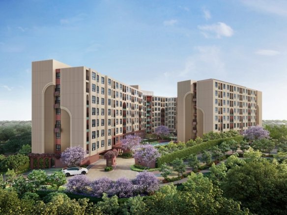 Modern beige apartment complex with curved towers surrounded by lush landscaping and flowering trees a driveway and car at the entrance
