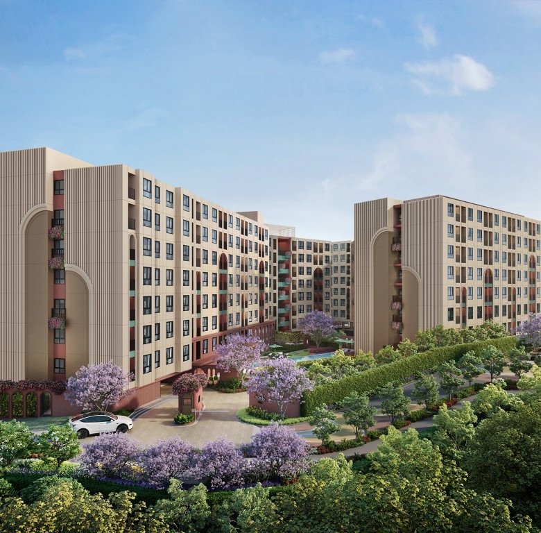 Modern beige apartment complex with curved towers surrounded by lush landscaping and flowering trees a driveway and car at the entrance